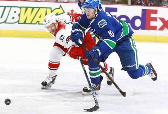 VANCOUVER, BC - JANUARY 6: Kris Versteeg #32 of the Carolina Hurricanes reaches to check Jared McCann #91 of the Vancouver Canucks during their NHL game at Rogers Arena January 6, 2016 in Vancouver, British Columbia, Canada. Vancouver won 3-2. (Photo by Jeff Vinnick/NHLI via Getty Images)