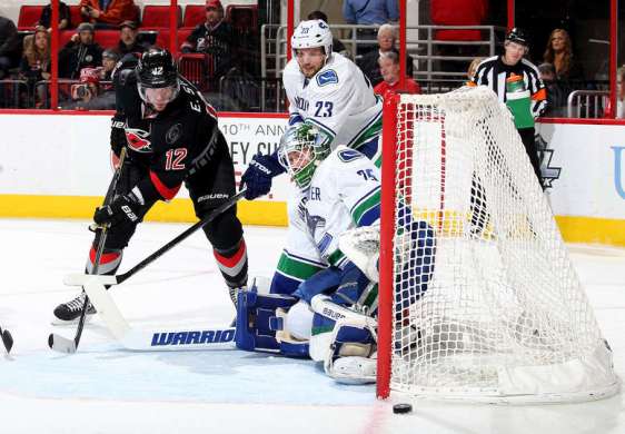 RALEIGH, NC - JANUARY 15: Jacob Markstrom #25 of the Vancouver Canucks goes down in the crease to protect the net while teammate Alexander Edler #23 defends and Eric Staal #12 of the Carolina Hurricanes looks to deflect the puck as it goes just wide of the goal during an NHL game at PNC Arena on January 15, 2016 in Raleigh, North Carolina. (Photo by Gregg Forwerck/NHLI via Getty Images)