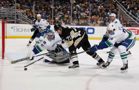 PITTSBURGH, PA - JANUARY 23: Evgeni Malkin #71 of the Pittsburgh Penguins moves the puck between the defense of Ryan Miller #30 and Emerson Etem #26 of the Vancouver Canucks at Consol Energy Center on January 23, 2016 in Pittsburgh, Pennsylvania. (Photo by Gregory Shamus/NHLI via Getty Images)