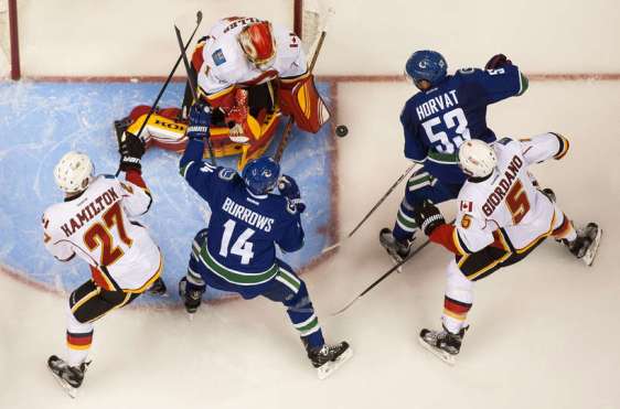 VANCOUVER, BC - OCTOBER 10: Bo Horvat #53 of the Vancouver Canucks shoots the puck past goalie Jonas Hiller #1 of the Calgary Flames while Dougie Hamilton #27 and Mark Giordano #5 of the Calgary Flames battle with Alexandre Burrows #14 in front of the net in NHL action on October, 10, 2015 at Rogers Arena in Vancouver, British Columbia, Canada. (Photo by Rich Lam/Getty Images)