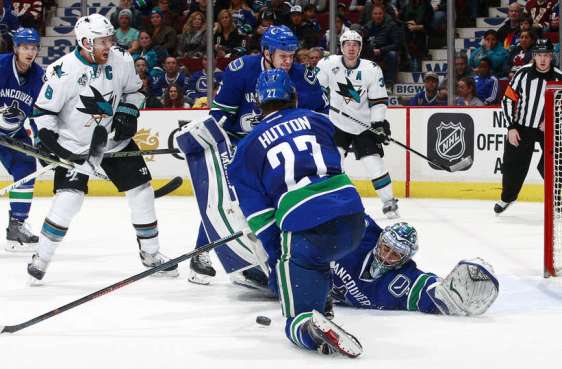 VANCOUVER, BC - FEBRUARY 28: Joe Pavelski #8 of the San Jose Sharks watches as Ryan Miller #30 of the Vancouver Canucks reaches back to make a save in front of Ben Hutton #27 and Derek Dorsett #15 of the Canucks during their NHL game at Rogers Arena February 28, 2016 in Vancouver, British Columbia, Canada. San Jose won 4-1. (Photo by Jeff Vinnick/NHLI via Getty Images)