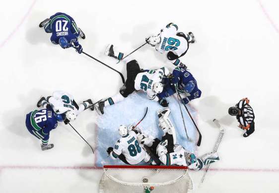 VANCOUVER, BC - MARCH 29: James Reimer of the San Jose Sharks sprawls in a crowd of players to make a save during their NHL game at Rogers Arena March 29, 2016 in Vancouver, British Columbia, Canada. San Jose won 4-1. (Photo by Jeff Vinnick/NHLI via Getty Images)